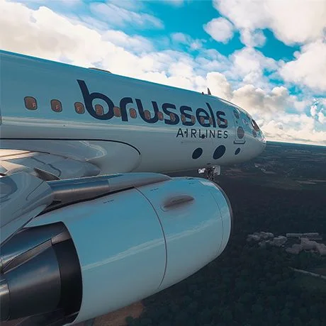 View of a Brussels Airlines aircraft fuselage and engine above the landscape in a flight simulator.